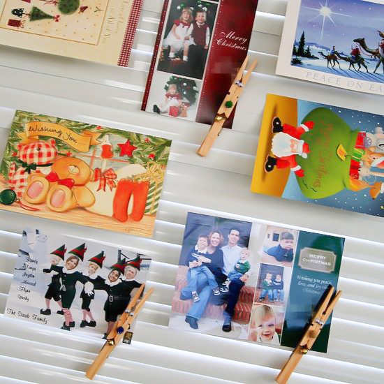 Christmas cards being clipped to blinds using reindeer pegs