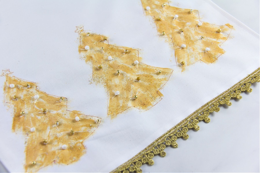 A christmas table runner with hand-painted christmas trees and beading.