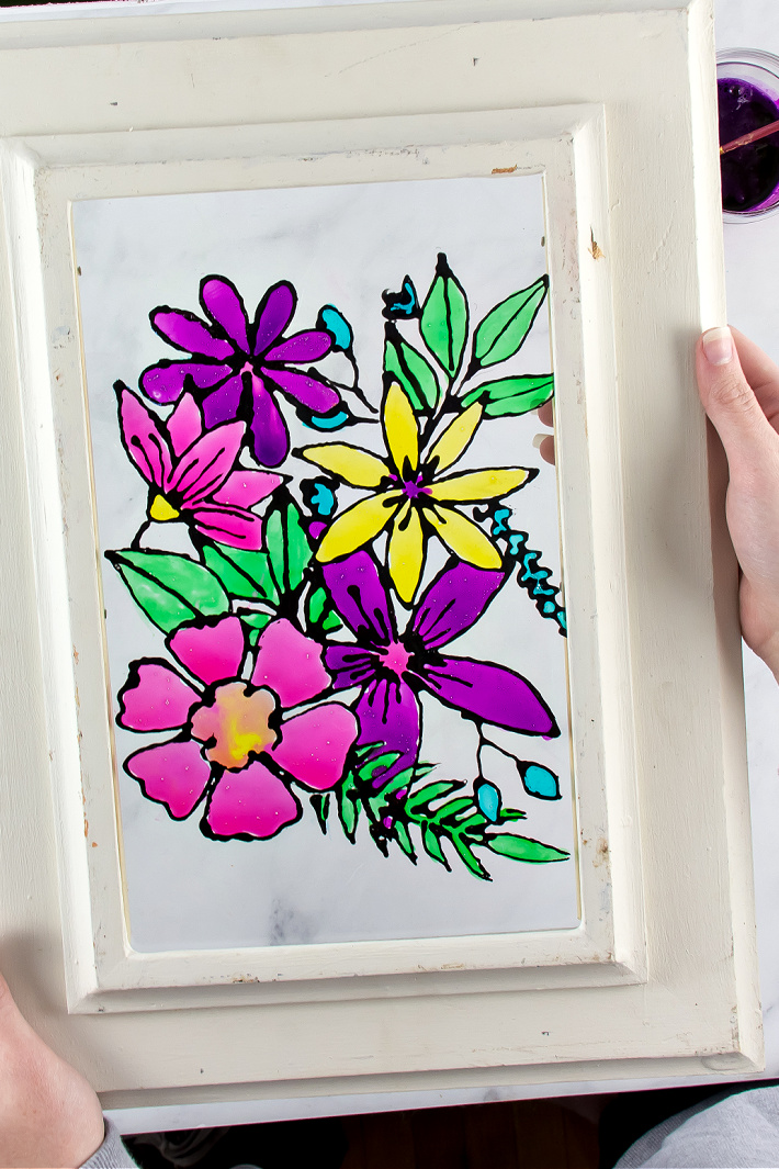 A faux stained flass window painted with flowers using homemade window paint.