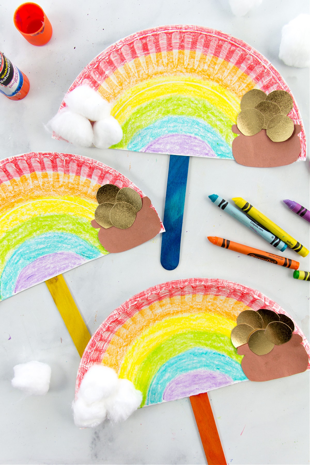a rainbow paper plate craft with cotton ball clouds and a pot of gold at the end of it