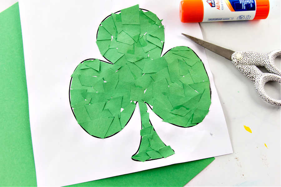 Green construction paper cut out and glued onto a picture of a shamrock.