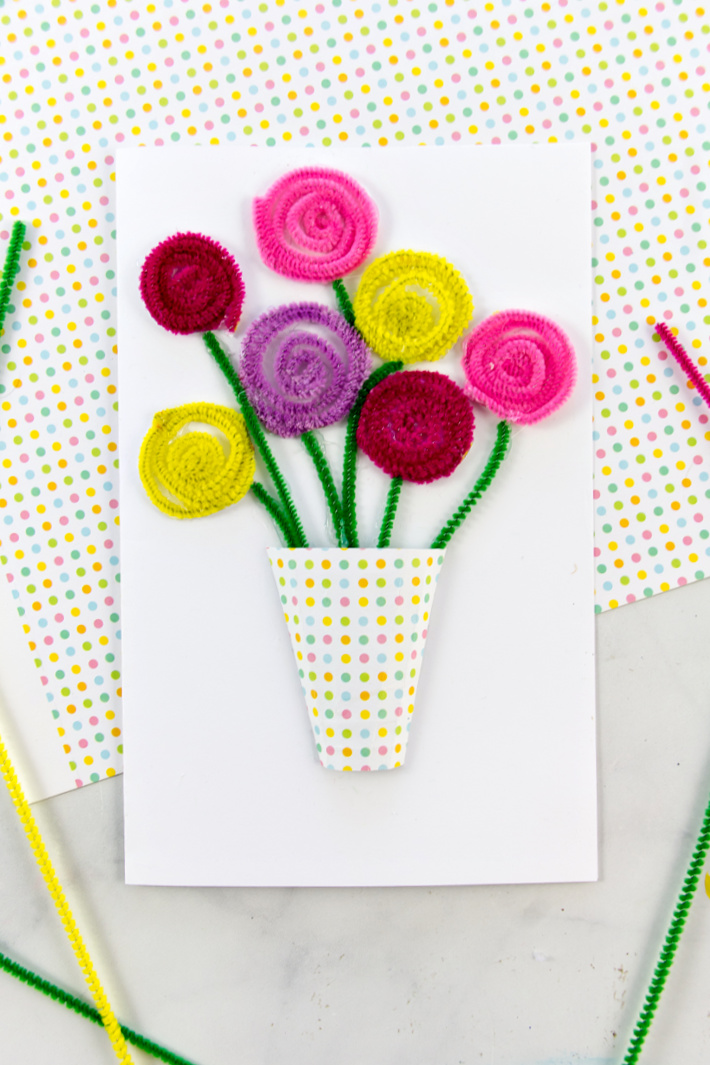 spring flowers made out of pipe cleaners and attached to a plain greeting card with a handmade vase made out of scrapbook paper.