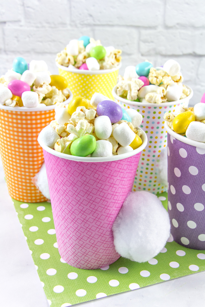 Paper cups wrapped with colorful scrapbook paper and pom pom attached to look like a cottontail.