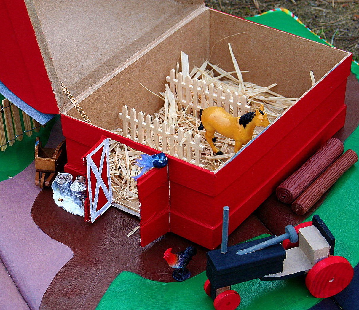 A paper mache chest converted into a barn that has horse stables inside.