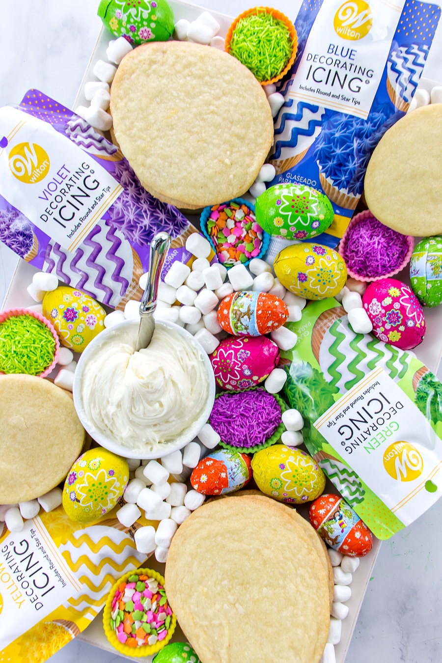Set up an Easter grazing board for kids that's filled with cookies and toppings for cookie decorating.