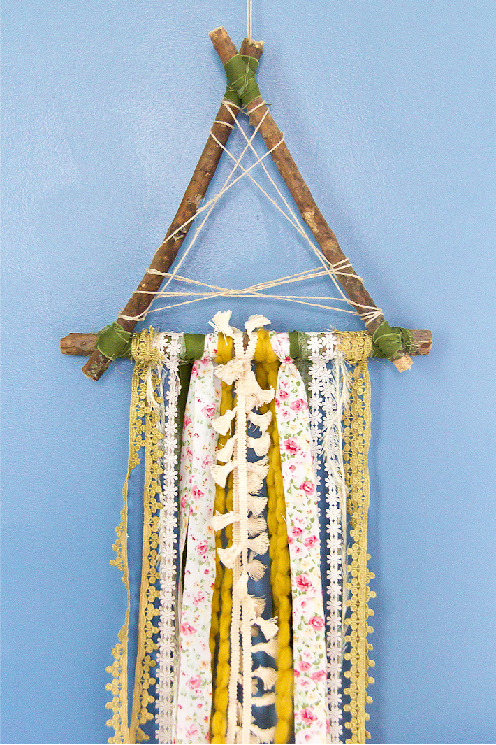 A wall hanging inspired by a dreamcatcher and made out of scrap ribbon, yarn, and fabric.
