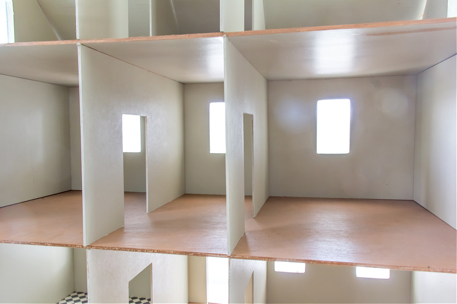 The inside of a basic wood dollhouse that needs to be decorated.