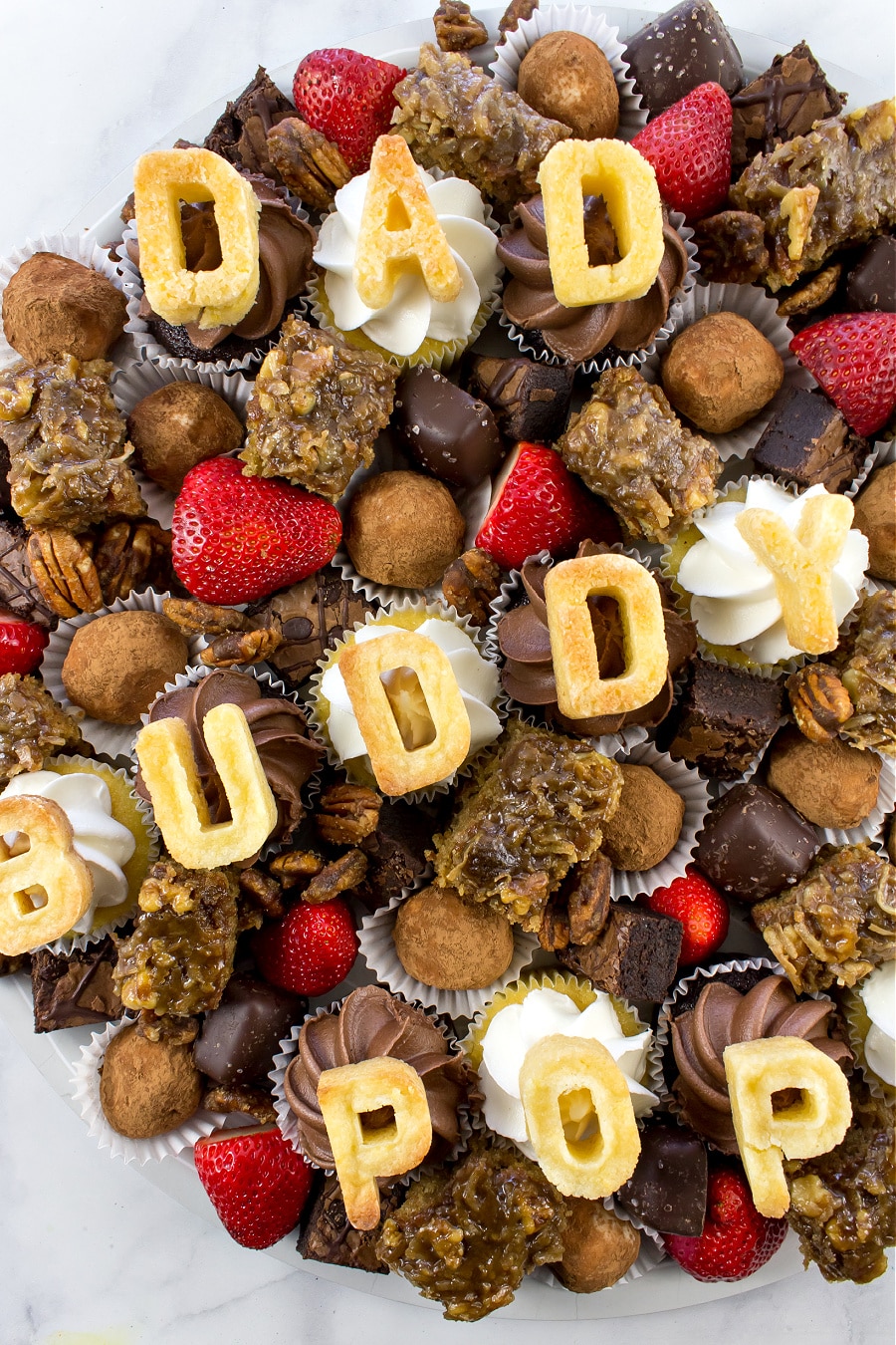 Fathers Day desserts food grazing board with cookies, cupcakes, bourbon balls, chocolates, fruit, brownies