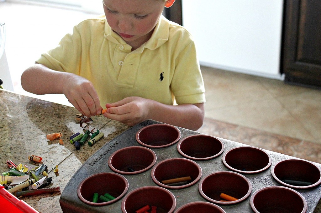 Broken crayons being unwrapped and sorted by color into silicone baking molds.