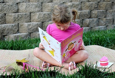 A girl reading Pinkalicious, making a crown and wand, and having a pink cupcake.