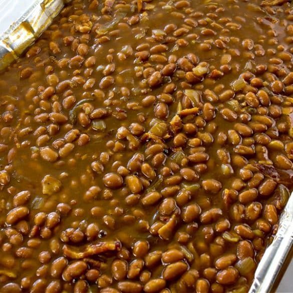a foil tray filled with baked beans and bacon and cooked in the oven for a potluck