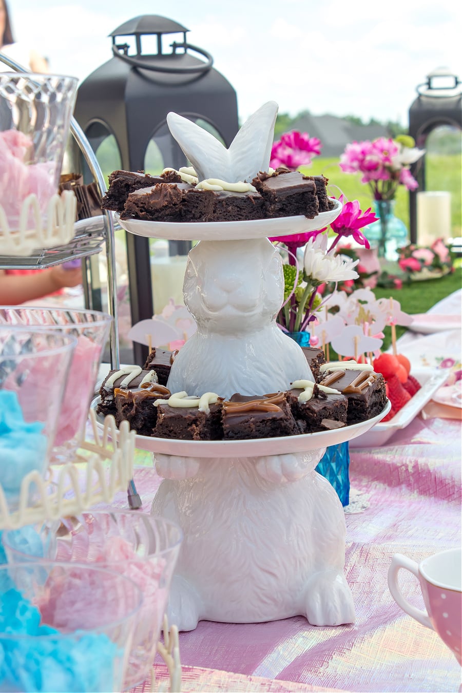 A ceramic tiered bunny food stand with brownie bites being served for a tea party.