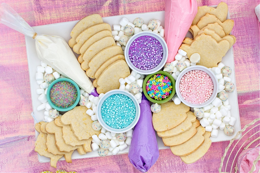 Tea pot and tea cup shaped cookies with toppings for kids to decorate cookies during a tea party.