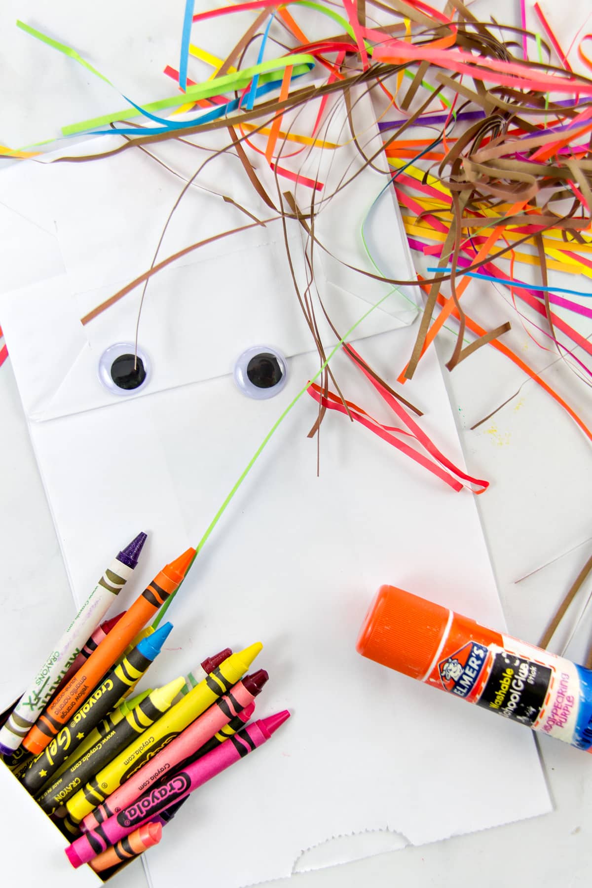 a paper bag, crayons, glue stick, googly eyes, and paper strips to make a scarecrow craft