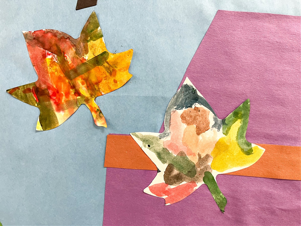 watercolor fall cut-out leaves painted by kids are used to decorate the classroom door for fall.