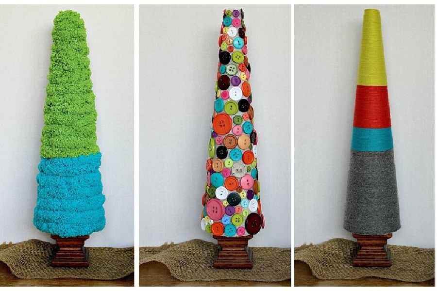 Styrofoam cones decorated with yarn and buttons to look like christmas trees