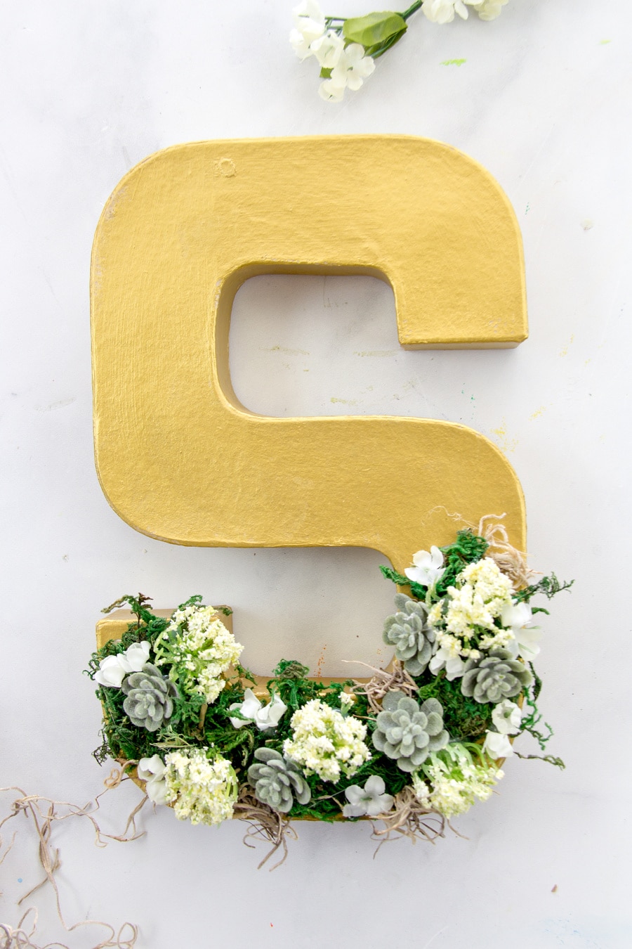 paper mache letter s decorated with faux succulents and moss