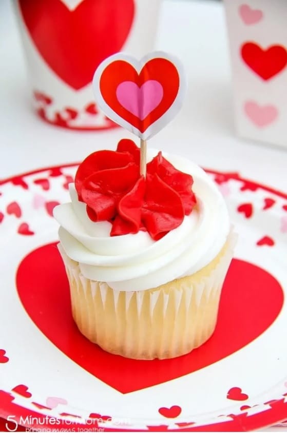 vanilla cupcakes topped with red and white icing and a heart cupcake topper for Valentines Day