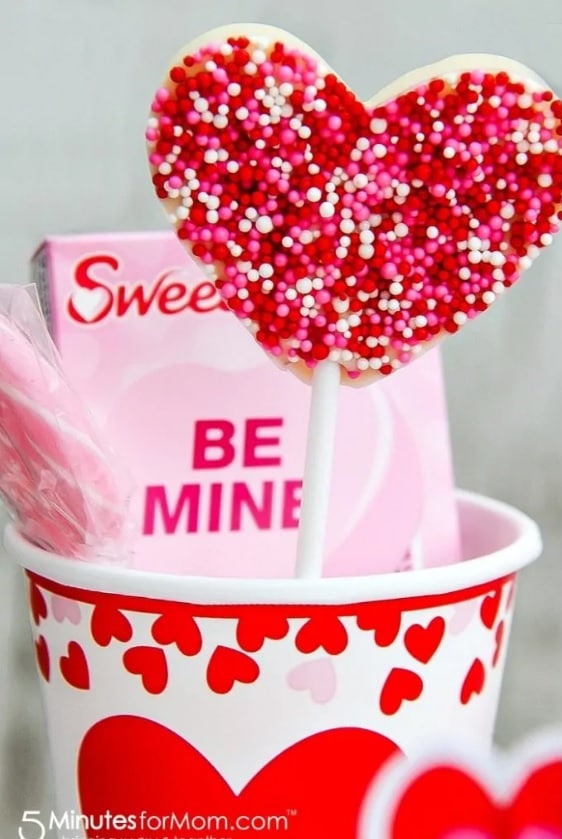 Valentine's Day paper drinking cups filled with yummy snacks like conversation hearts and a lollipop