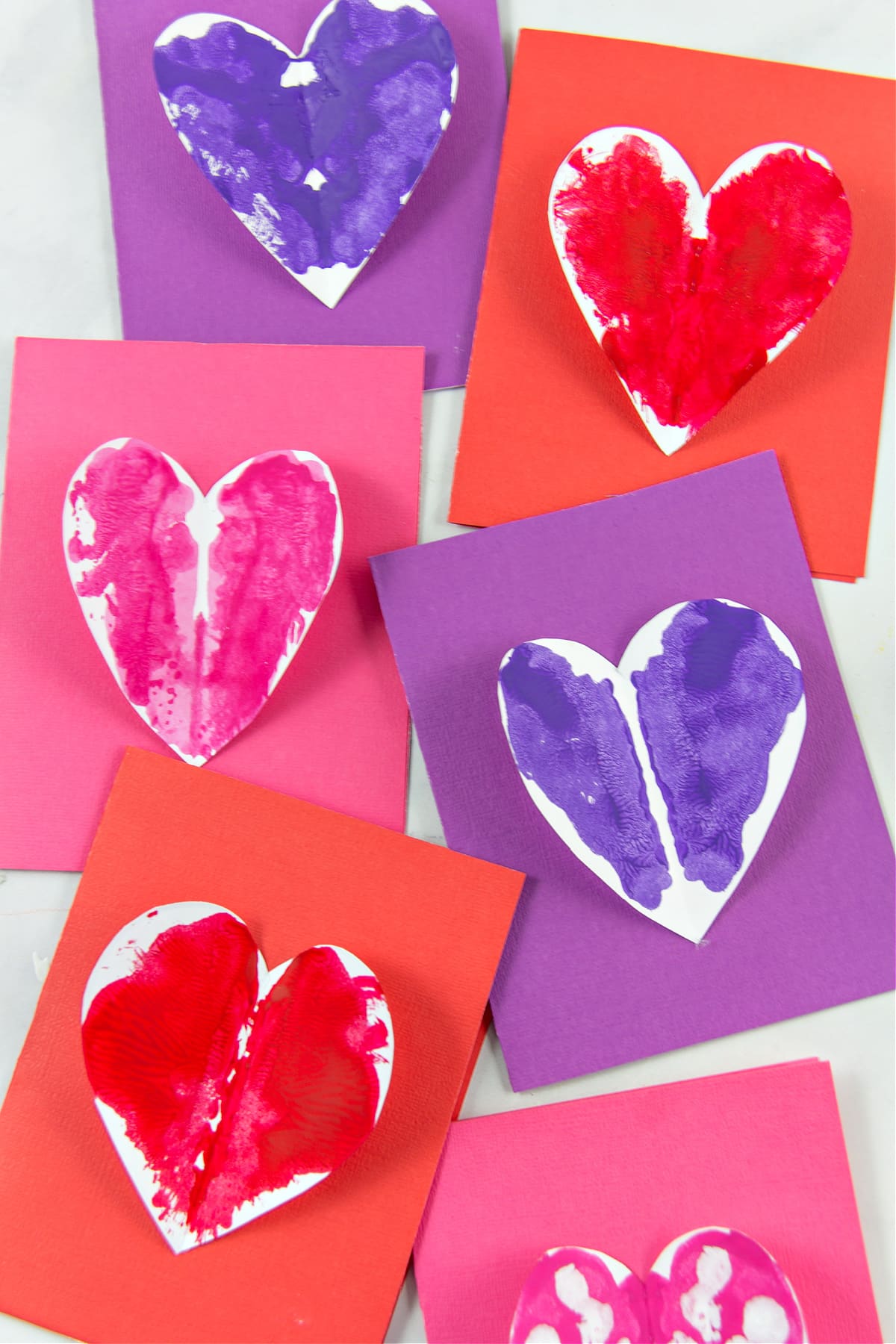 Painted hearts attached to construction paper cards for Valentine's Day