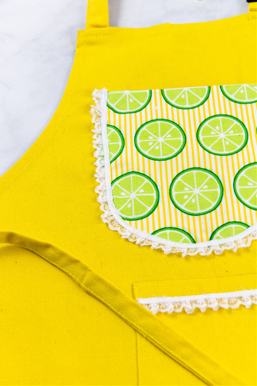 A bright yellow apron for kids with pockets and citrus patterned fabric pocket