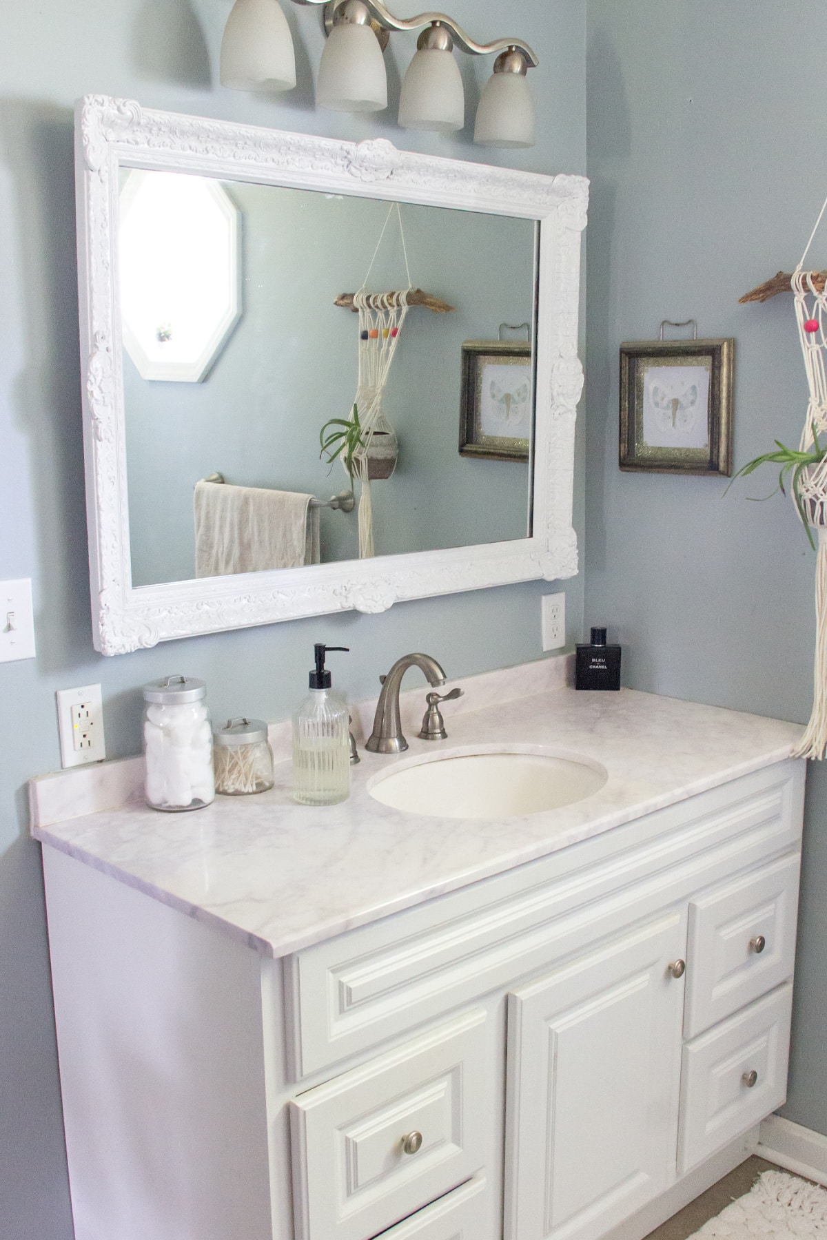 a white and grey bathroom with a white framed mirror