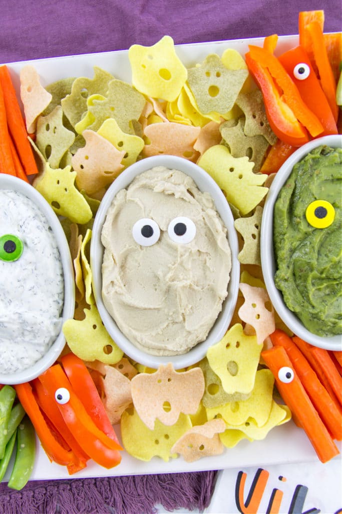 healthy halloween snack board tray with dips, chips, and vegetables
