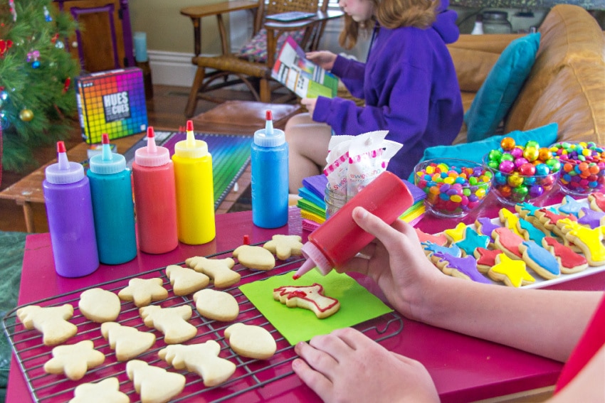 a child using a squeeze bottle to decorate colorful christmas cookies