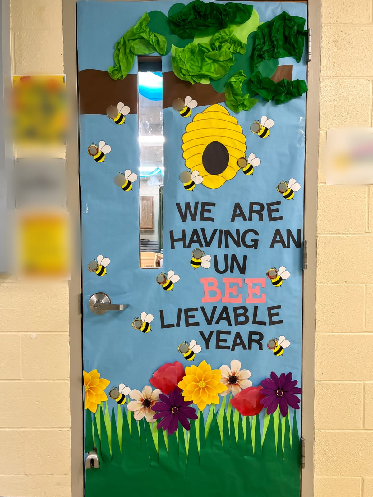 a spring bee theme classroom door with pretty flowers and green on the tree