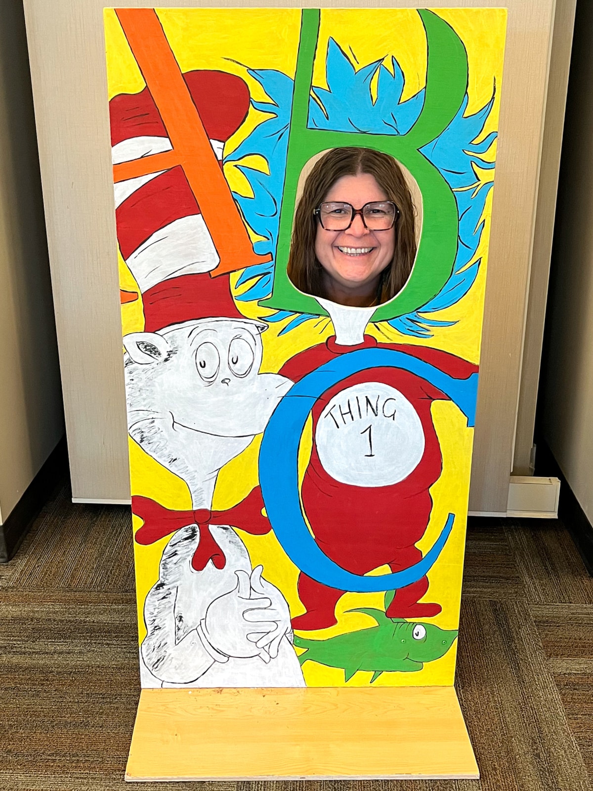 diy wood dr seuss themed photo booth with cat in the hat, thing 1, a green fish, and the letters a b c.
