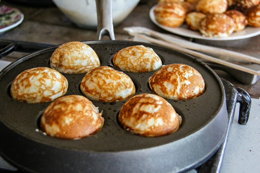 mini ebelskiver pancakes that have been flipped in an ebelskiver pan