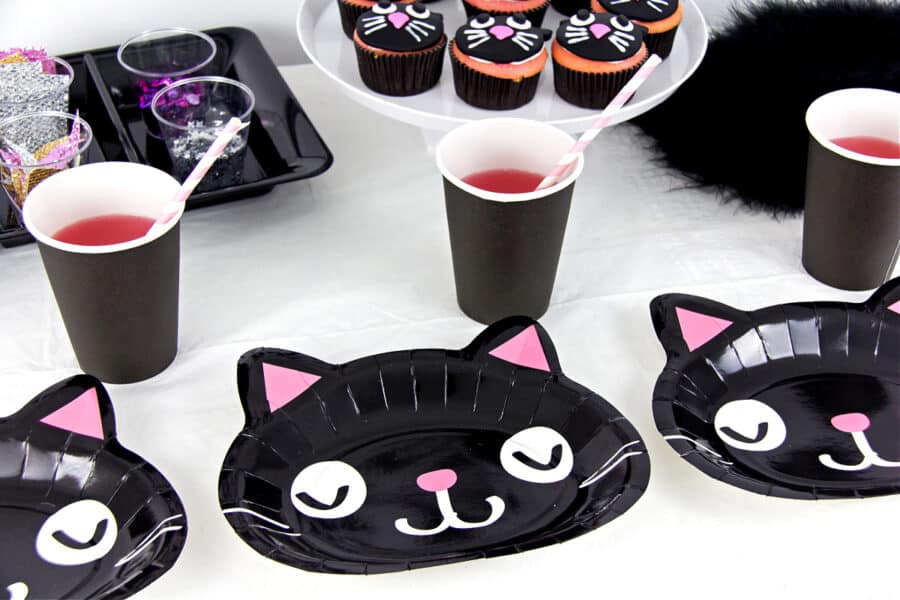 A party table with black cat party plates, black cups, and black cat cupcakes.