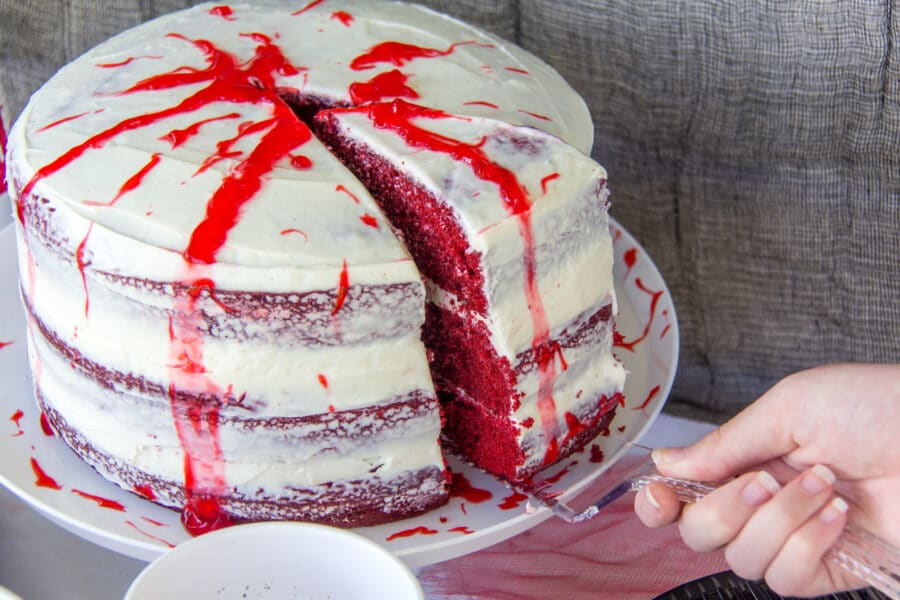a red velvet naked cake with white frosting and blood dripping over the sides